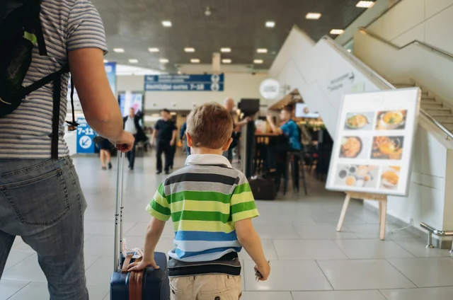 Father and cute boy in airport with backpack and suitcase. Travelling with kids